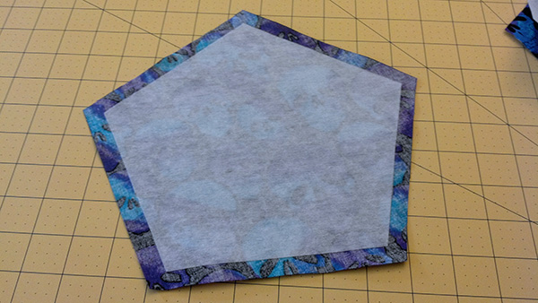 The interfacing pentagon attached to the back side of the fabric pentagon, so that it will be on the inside of the pillow when the die is sewn up.